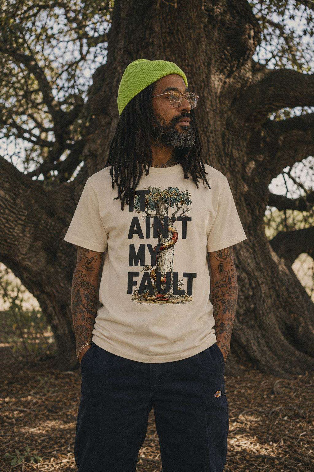 Model beneath an oak tree wearing the It Ain't My Fault tee.